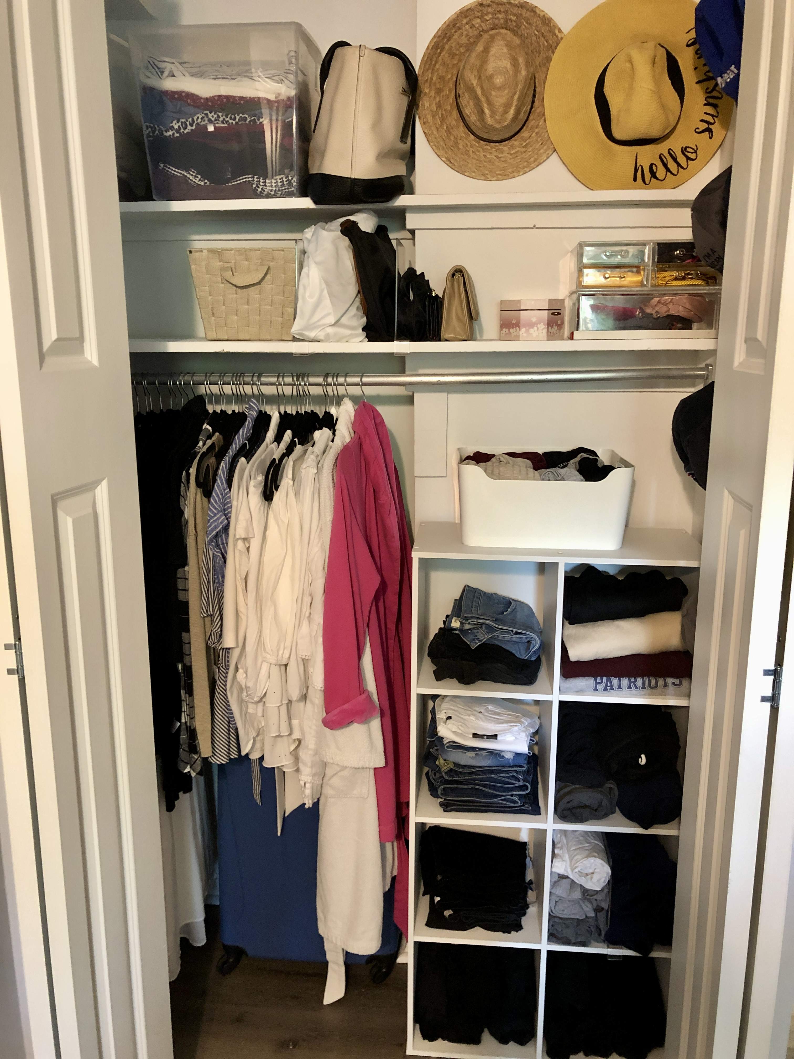 Organized closet with clothes categories and contained in a white cube unit; hanging clothes on matching black velvet hangers