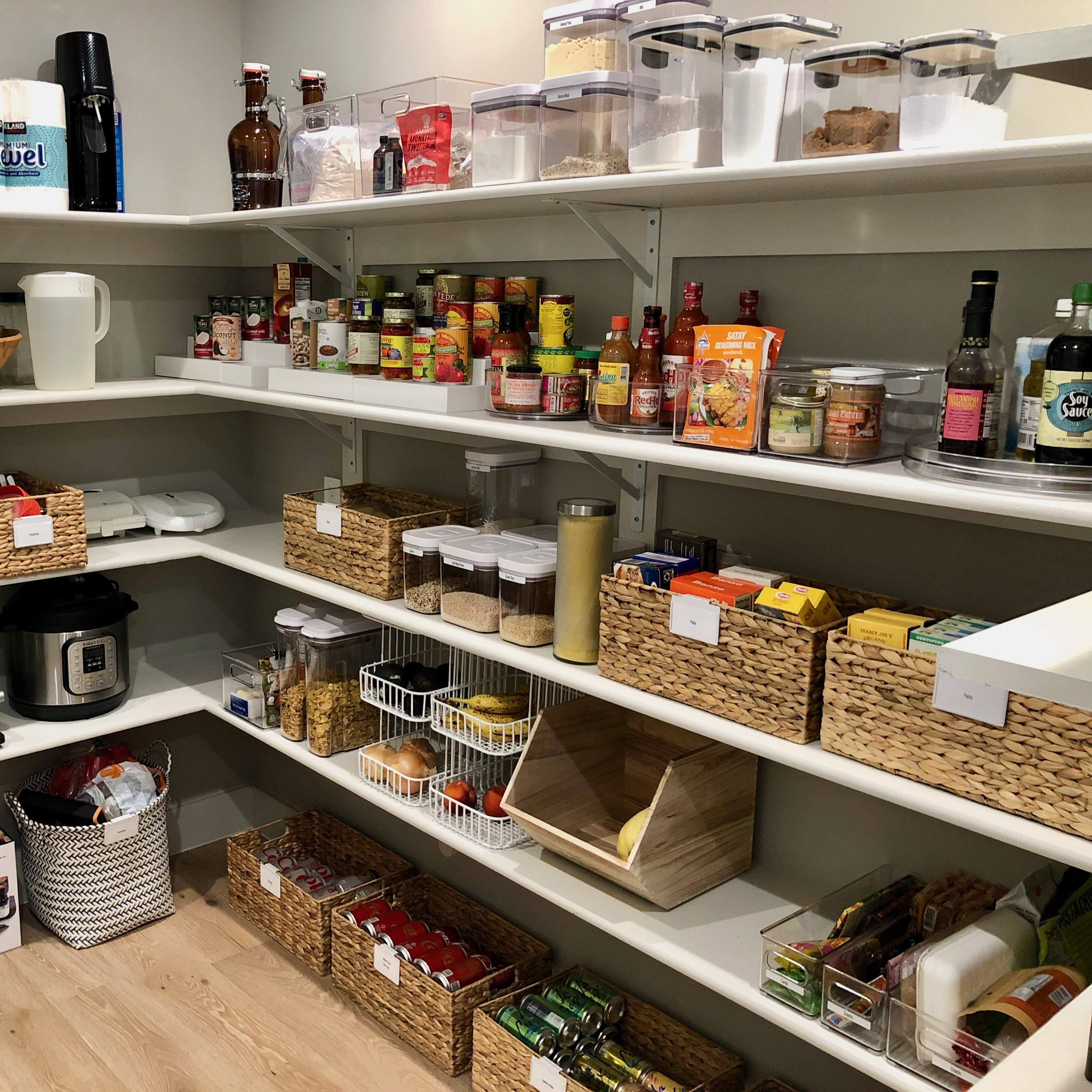 Kitchen pantry with grocery items organized on shelves. Baskets and bins hold various categories