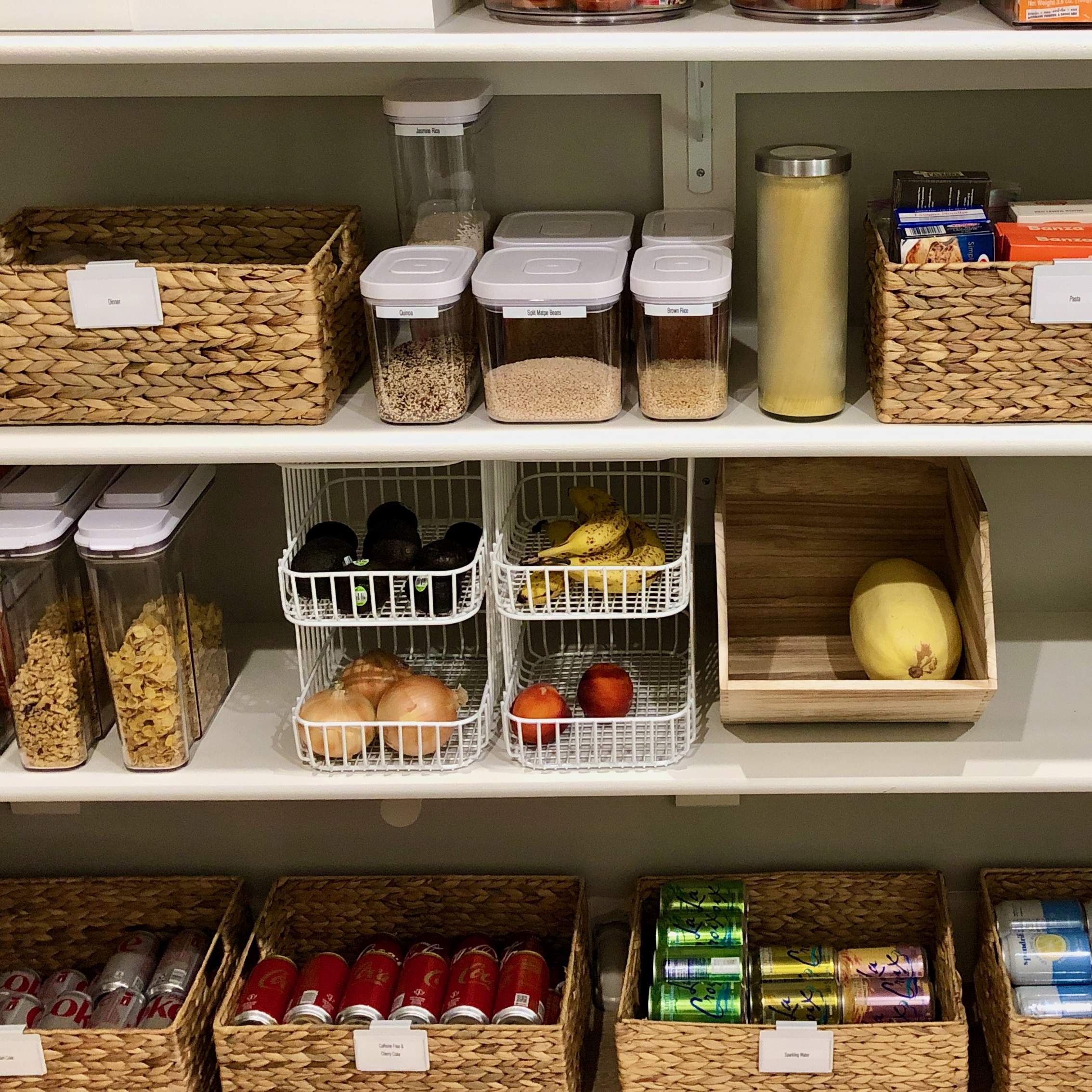 Kitchen pantry with grocery items organized on shelves. Baskets and bins hold various categories