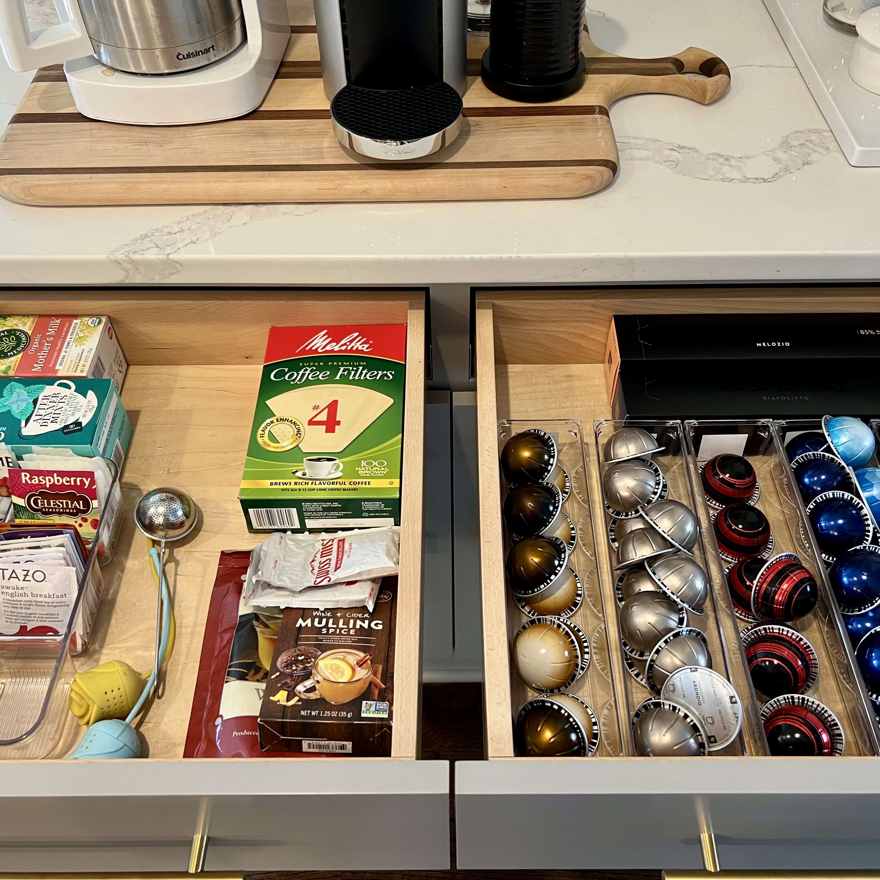 A coffee and tea drawer is organized beneath a kitchen drink station. Coffee pods are contained in drawer bins.