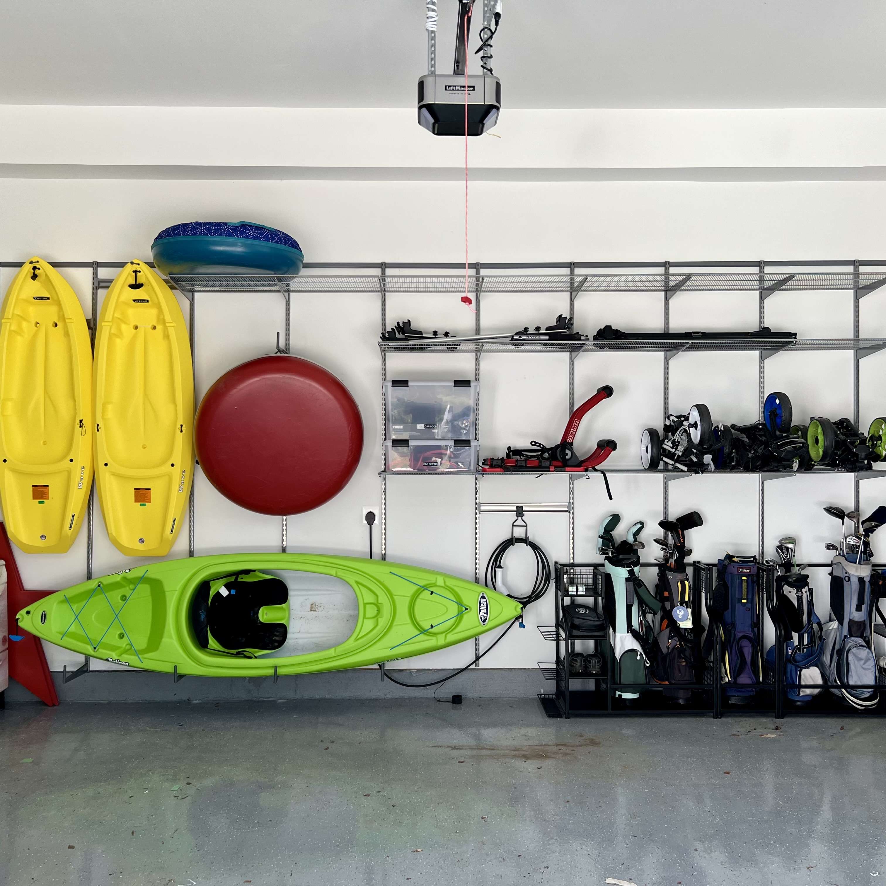An organized garage with custom shelving installed. Outdoor and sport equipment and lawn tools are organized on the shelves.