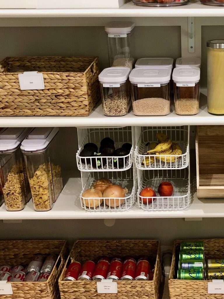 Kitchen pantry with grocery items organized on shelves. Baskets and bins hold various categories.