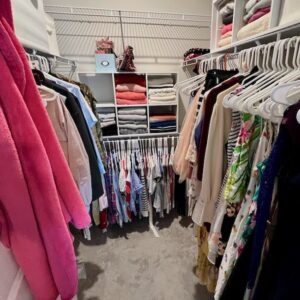 A walk-in closet after its fall closet organization switch. A 6 unit cube organizer sits on the shelf to store sweaters. Summer and warm weather clothing is stored up high.