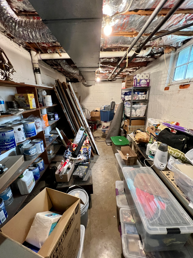 A basement storage space is overflowing with items.